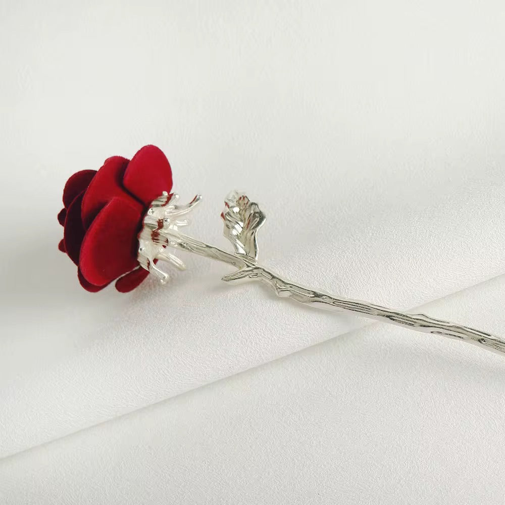 Side view of a red velvet rose hair stick showcasing its dimensional petals and sculpted silver-tone floral stem.