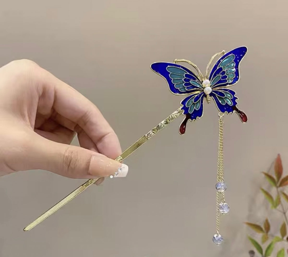 Sapphire blue butterfly hair stick featuring turquoise wing accents, a gold-tone stem, and dangling crystal-like beads.