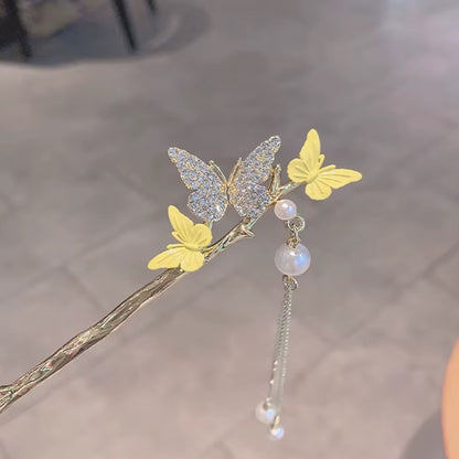 Gold-tone hair stick featuring a sparkling crystal-like butterfly, two yellow butterflies, and delicate dangling pearl-like accents.