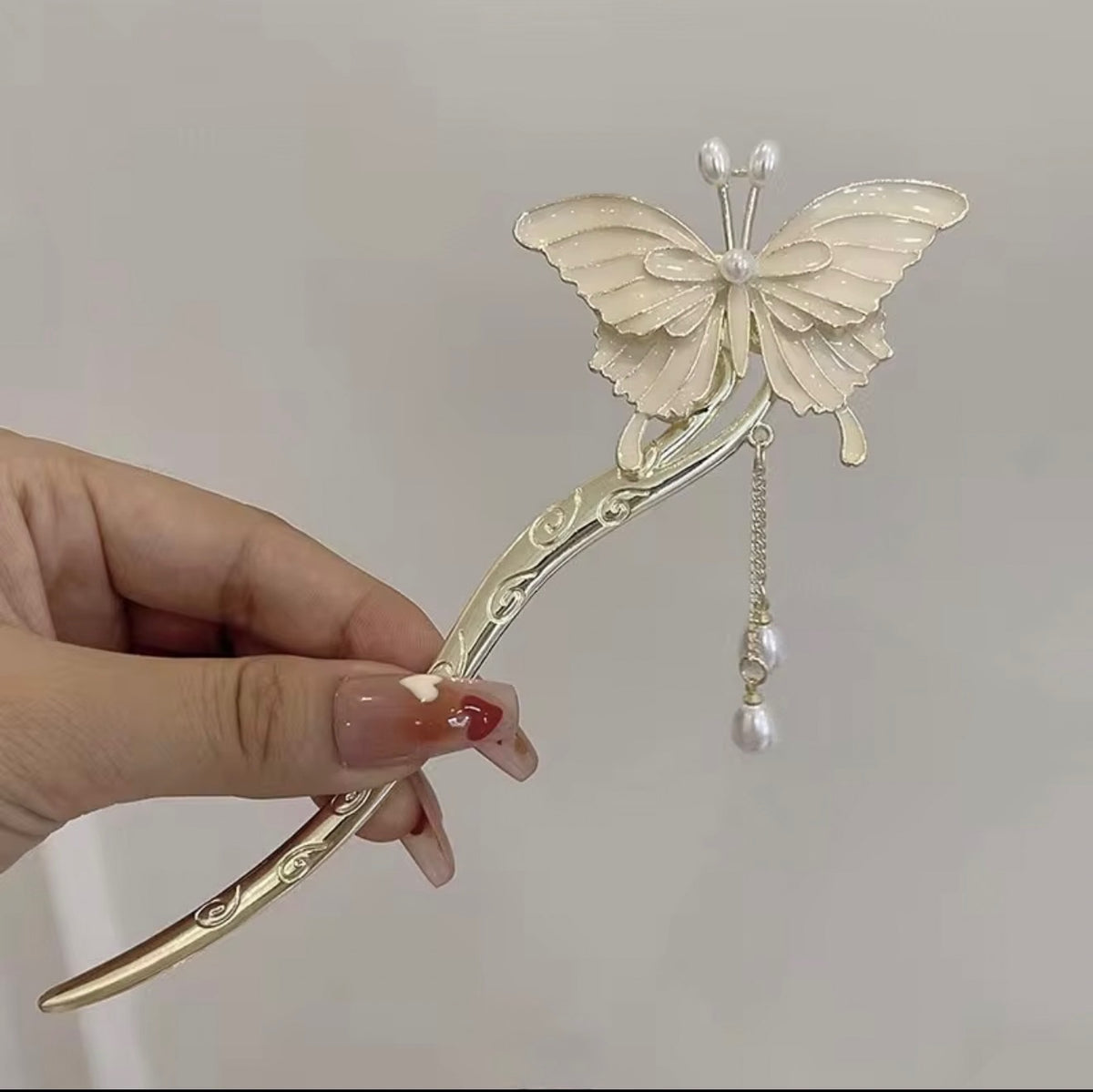 Ivory butterfly hair stick with gold-tone sculpted stem, delicate wing detailing, and dangling pearl-like accents.